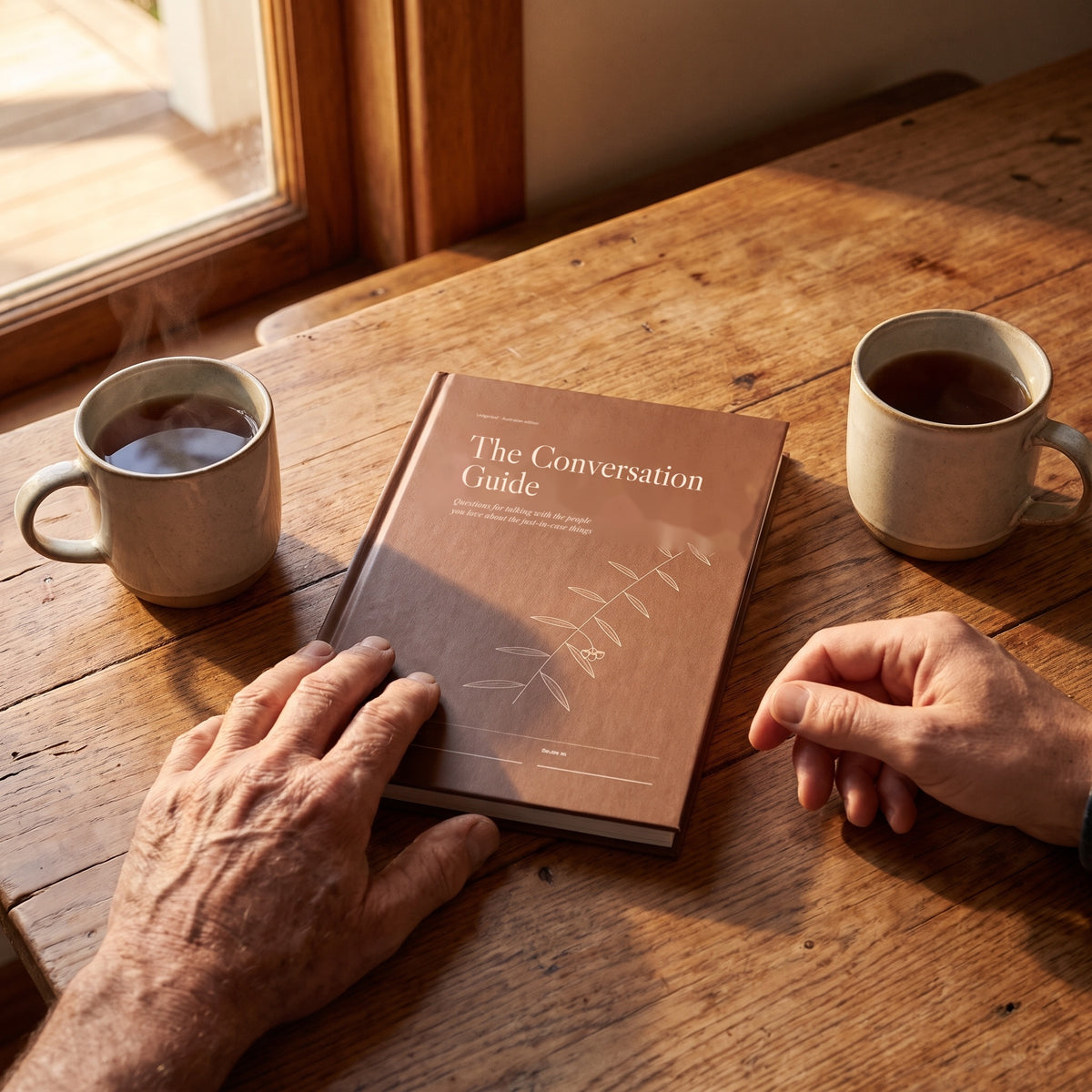 The Conversation Guide on a kitchen table between two mugs of tea, a father and son mid-conversation